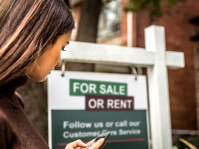 Woman photographing a real estate sign for a nice house for sale in downtown.