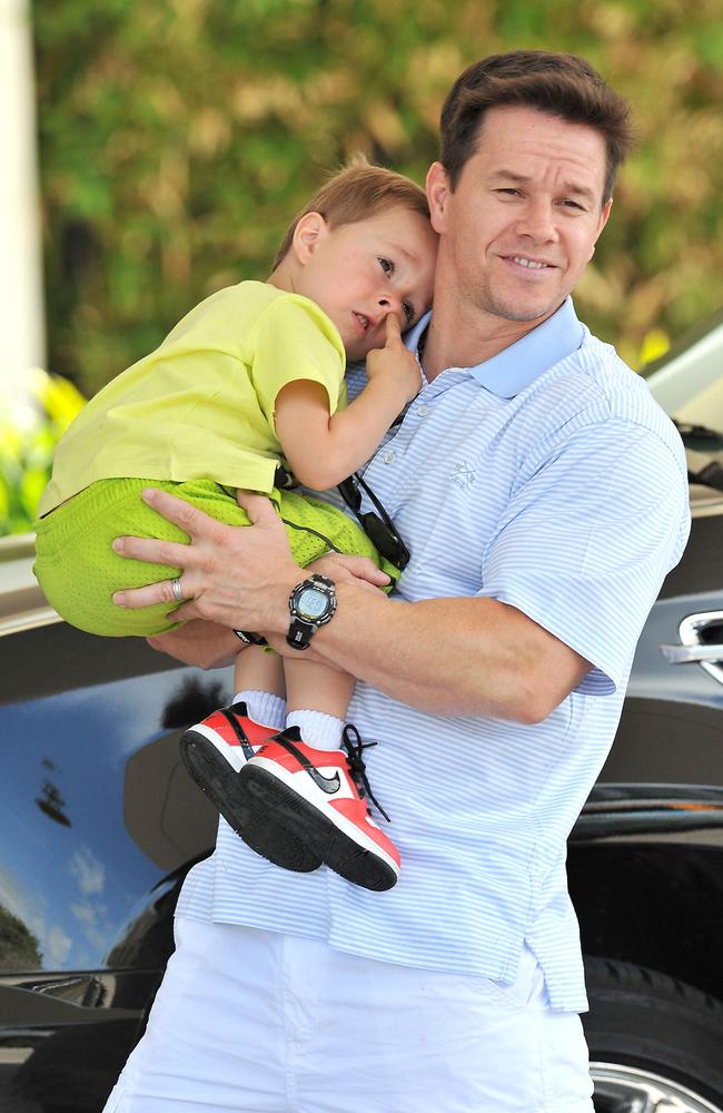 Fossicking ... Mark Wahlberg carries son Brendan — who is otherwise preoccupied — on a day out in Miami. Picture: Australscope