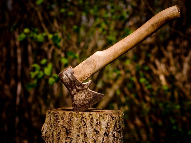An axe stuck in a piece of wood.
