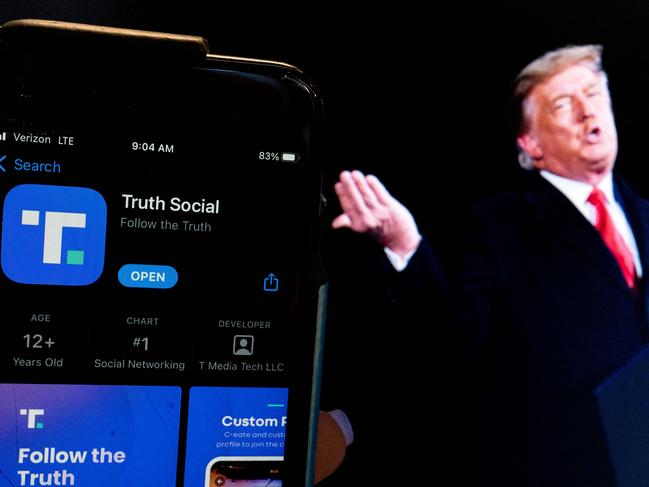 This photo illustration shows an image of former President Donald Trump next to a phone screen that is displaying the Truth Social app, in Washington, DC, on February 21, 2022. - Donald Trump's new social media app started a gradual rollout late February 21st and should be "fully operational" by late March, potentially raising the former president's profile more than a year after he was banned by major platforms. Trump has described Truth Social as an alternative to Facebook, Twitter and YouTube, all of which banned him following the assault on the US Capitol by his supporters on January 6, 2021. The former president has been accused of inciting his followers to use force in a bid to overturn the result of the 2020 election. (Photo by Stefani Reynolds / AFP)