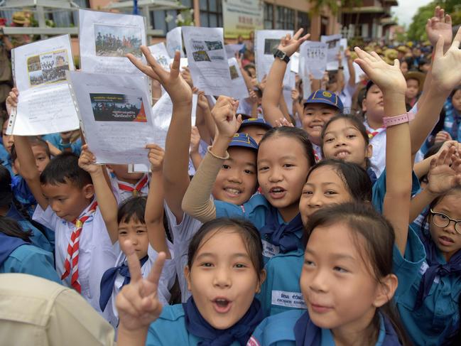 Thai students smile as they hold pictures of 12 boys and a football coach in front of the hospital after the group were admitted to recover. Picture: AFP