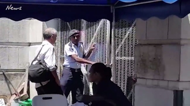 John Nikolic walks with a police officer in Suva