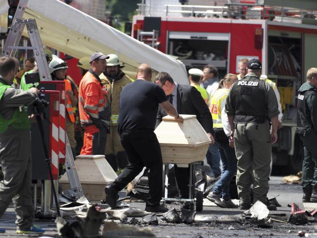 Undertakers bring two wooden coffins to the place of the accident.