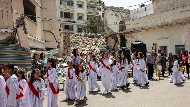 Child deaconesses walk past the rubble of a collapsed building in a procession during the Palm Sunday service, marking the start of Holy Week for Orthodox Christians. Picture: AFP