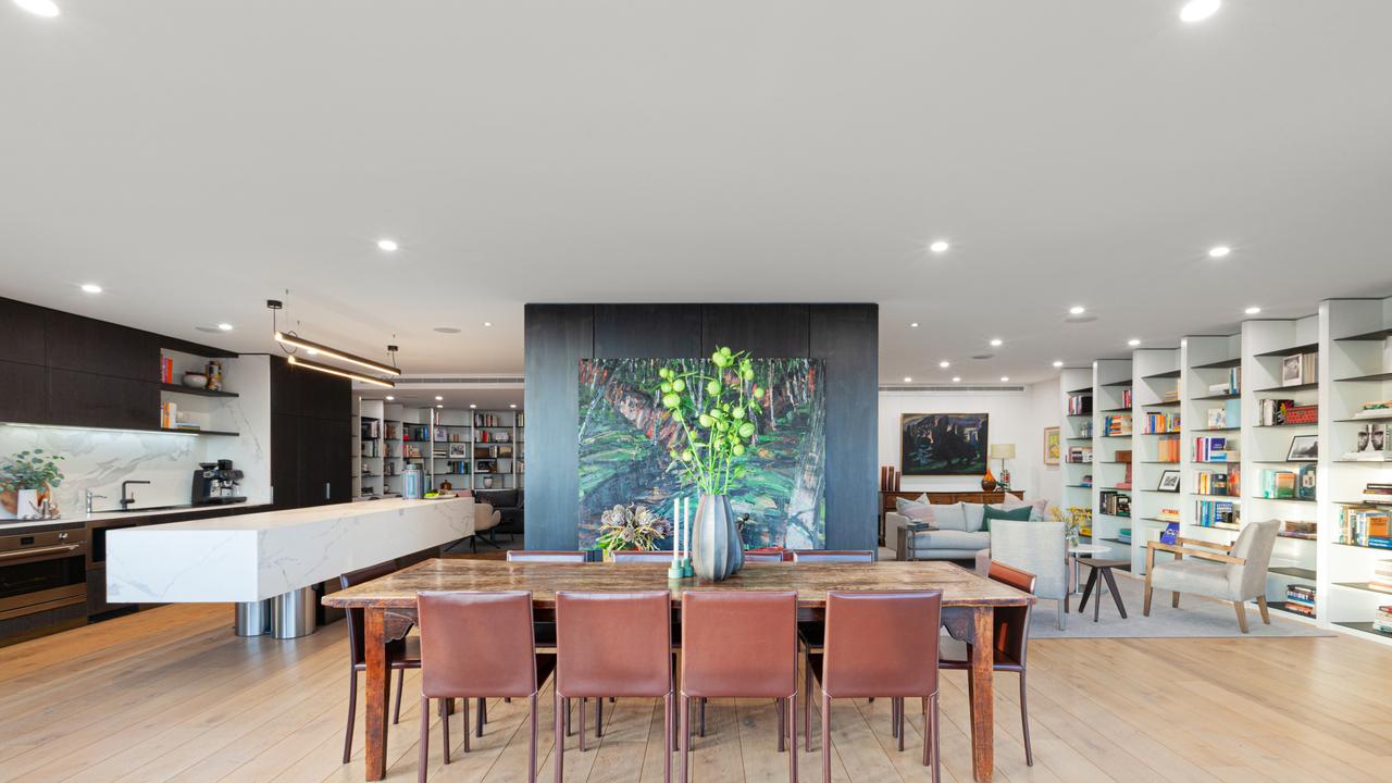 Curved custom bookshelves and gallery lighting give the penthouse’s main living space a refined, modern feel.