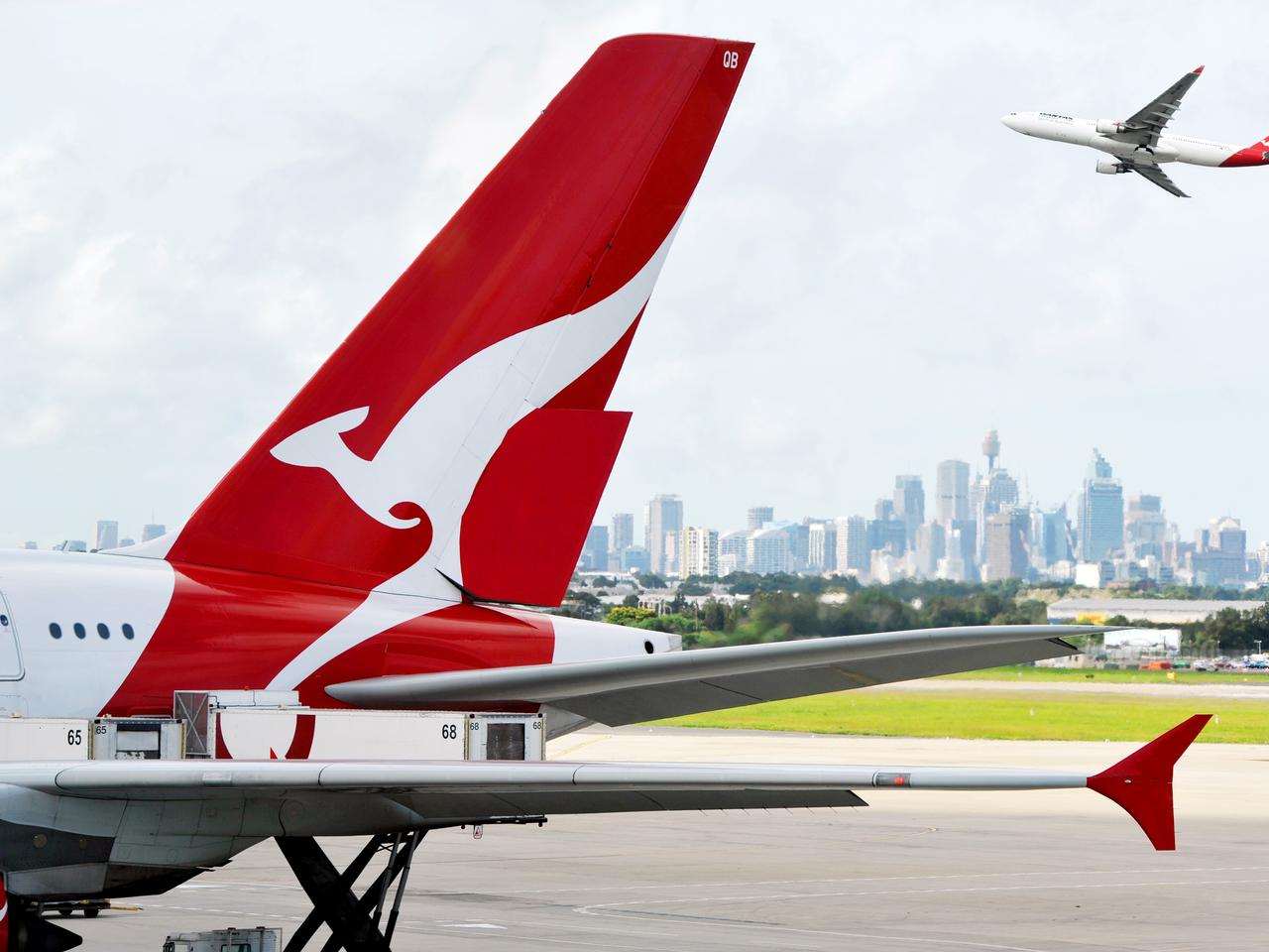 "Sydney, Australia - March, 14th 2012: Quantas aeroplanes and tail fin with the distant view of downtown Sydney - Sydney Airport"