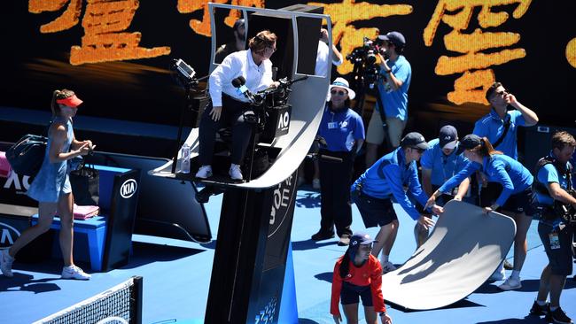 Officials remove part of the umpire’s canopy shade after it was sent flying by spider-cam.