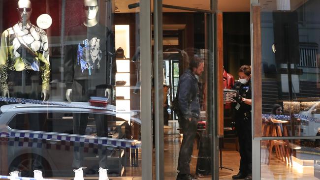 A police officer speaks to a man inside the Berluti store in Collins Street after it was ram raided. Picture: NCA NewsWire/ David Crosling