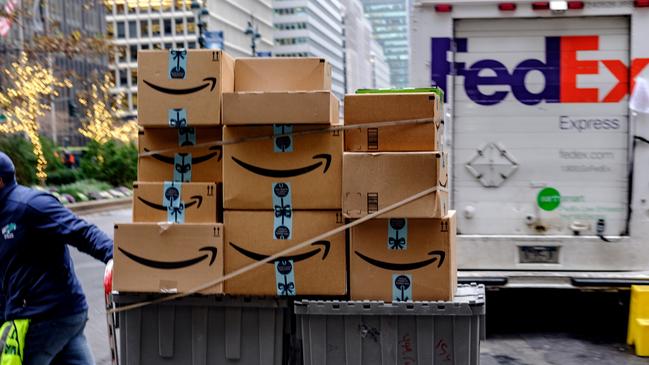 A worker pushes Amazon.com Inc. packages in front of a FedEx Corp. delivery truck in New York, U.S., on Monday, Nov. 26, 2018. Americans spent $50.6 billion online this month through Sunday, a 20 percent increase from a year ago and spearheaded by a 24 percent surge to $6.2 billion on Black Friday, according to Adobe Analytics. Cyber Monday is expected to add another $7.8 billion -- an 18 percent year-over-year gain for that day. Photographer: Christopher Lee/Bloomberg