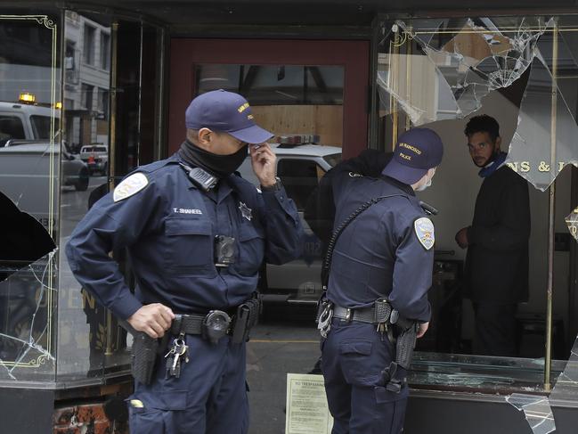 Police officers talk to a man through a broken window of Goorin Bros. Hat Shop in San Francisco. Picture: AP