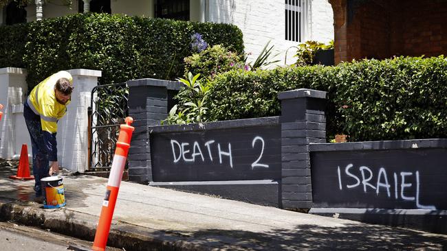 A cleaner paints over anti-Semitic graffiti sprayed on homes in Woollahra, Sydney, after the area’s second attack on Wednesday. Picture: Sam Ruttyn