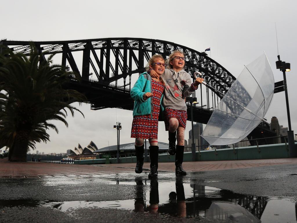 Sisters Ashley 7 and Emma Williams 9 pictured at Milsons Point enjoying the wet weather in Sydney today. Picture: Toby Zerna