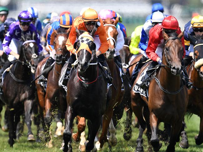 Jockey Tye Angland rides Ace High (centre left orange and white silks) and Stephan Baster rides Runaway (second from right) as they lead the field through the first turn of the Melbourne Cup at Flemington Racecourse in Melbourne, Tuesday, November 6, 2018. (AAP Image/Julian Smith) NO ARCHIVING, EDITORIAL USE ONLY