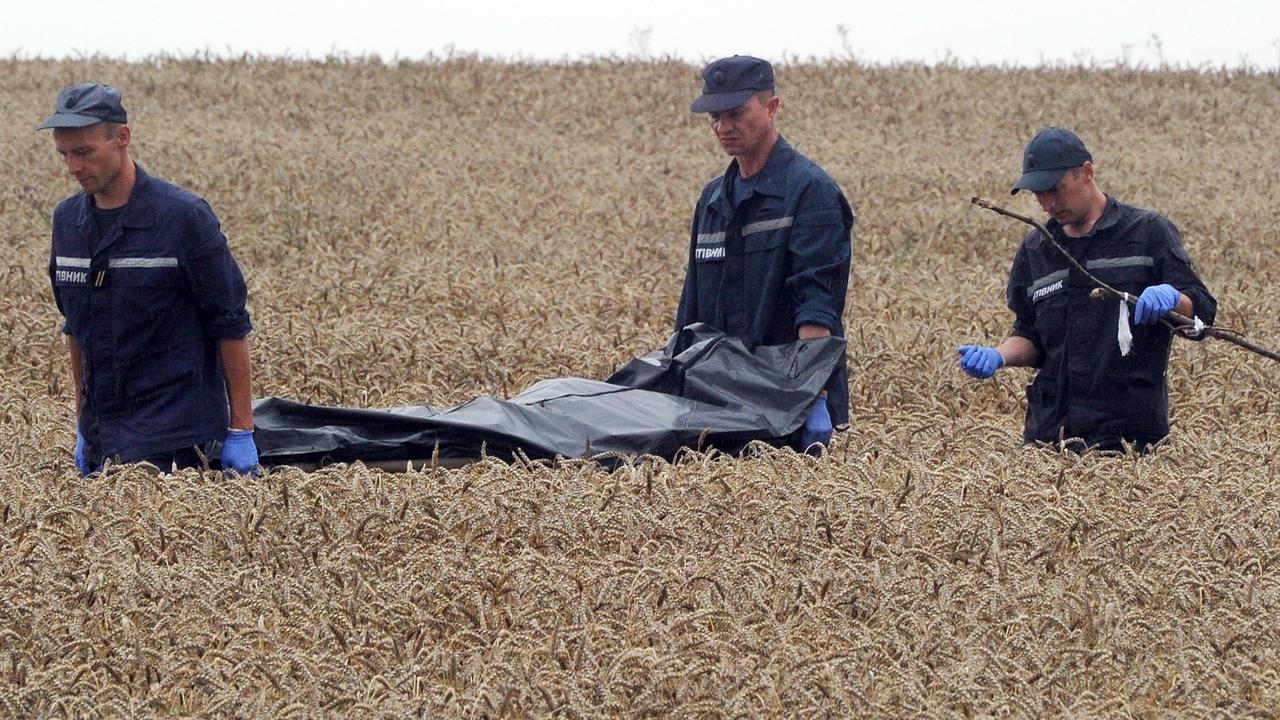 Ukrainian rescue workers carry the body of a victim on a stretcher through a wheat field at the site of the crash. Picture: Dominique Faget/AFP