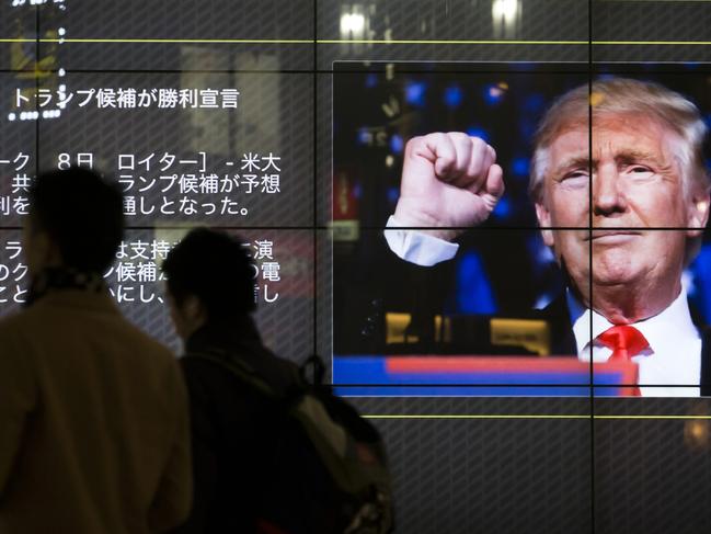 Pedestrians walk past a large television screen during a news broadcast of the U.S. presidential election result in Tokyo, Japan, on Wednesday, Nov. 9, 2016. Japanese shares tumbled the most since June's Brexit vote and the yen surged with investors rushing to haven assets as Donald Trump unexpectedly racked up victory after victory in the U.S. election to become the nation's 45th president. Photographer: Tomohiro Ohsumi/Bloomberg