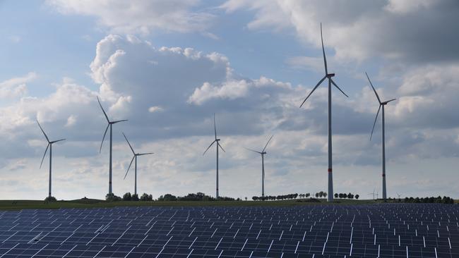 Wind turbines spin behind a solar energy park near Prenzlau, Germany.