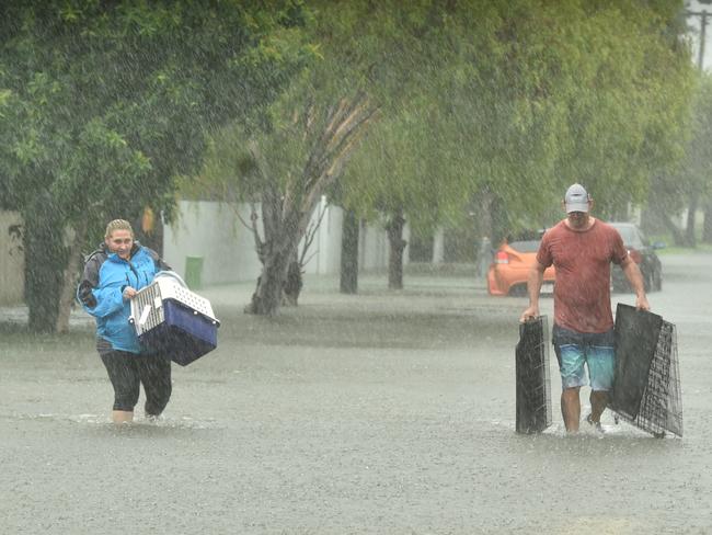 Sunday February 2. Heavy rain lashes Townsville causing flash flooding. Jo Martin carries her cat Kramer and Peter Sharpe in Carmody Street, Rosslea. Picture: Evan Morgan