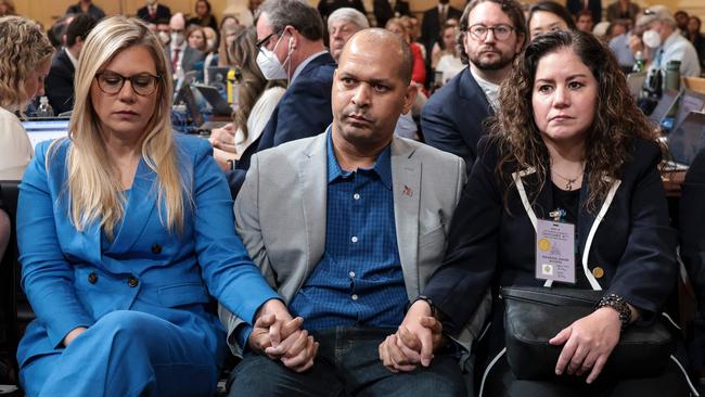 (L-R) Erin Smith, the widow of DC Metropolitan Police Officer Jeffrey Smith, Capitol Police Sgt Aquilino Gonell, and Sandra Garza, the long-time partner of fallen Capitol Police Officer Brian Sicknick, hold hands as they listen. Picture: AFP