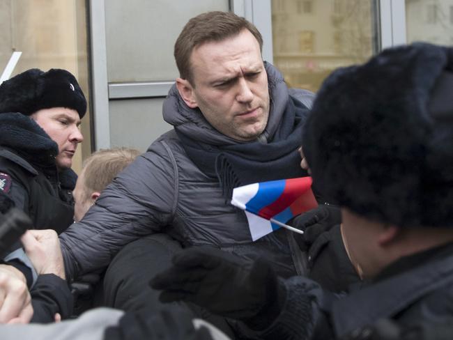 Alexei Navalny, centre, is detained by police officers in Moscow, and was barred from joining the presidential campaign due to a criminal conviction widely seen as a political punishment for his opposition activities. Picture: Evgeny Feldman/AP