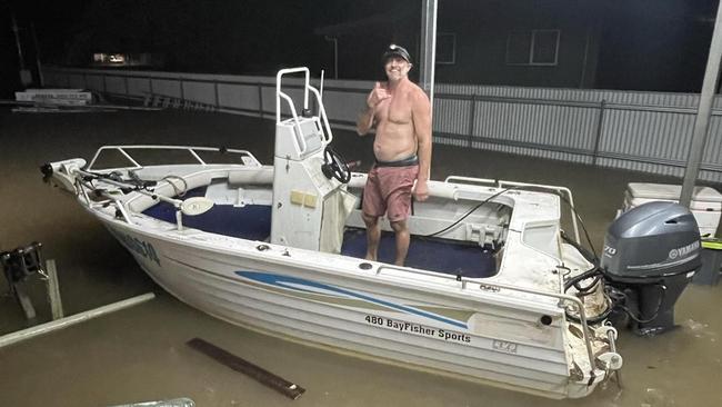 Cardwell resident Brent Churton launches a dinghy from his car port before whisking nearby residents to safety before their home flooded.