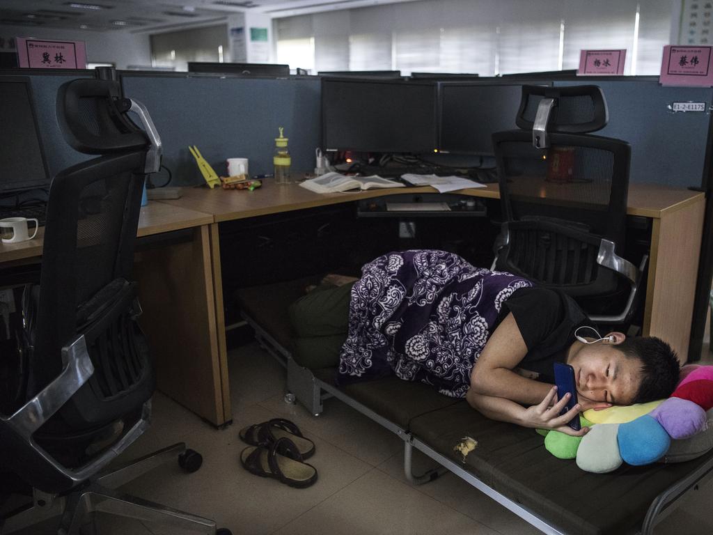 A Huawei employee watches a program on his smartphone as he rests in his cubicle. Picture: Getty