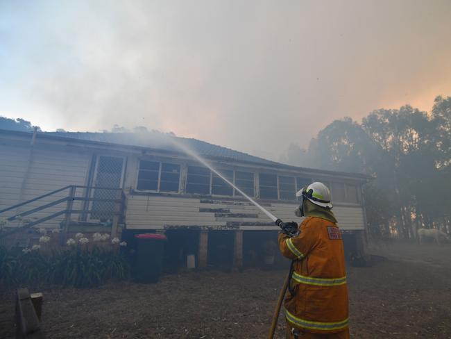 A firefighter hoses down a property in the hope of saving it from nearby bushfires around the town of Nowra in the Australian state of New South Wales on December 31, 2019. - Thousands of holidaymakers and locals were forced to flee to beaches in fire-ravaged southeast Australia on December 31, as blazes ripped through popular tourist areas leaving no escape by land. Picture: Saeed Khan/AFP