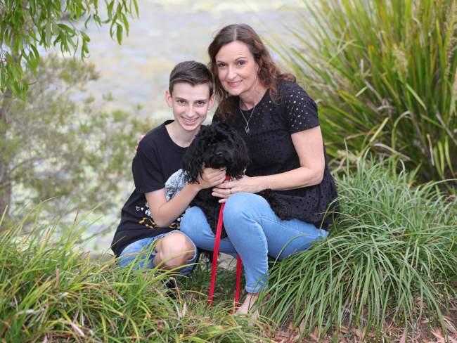 Lynne Stewart and son Alex with their dog Charley reunited at Pacific Pines after she was stuck overseas for months. Picture Glenn Hampson