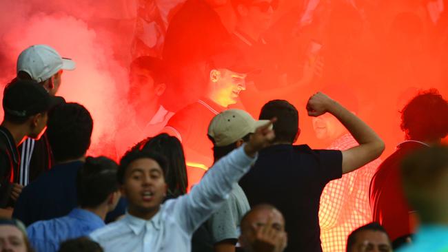 A supporter removes a flare after it was ignited in the Melbourne Victory supporters area of the crowd.