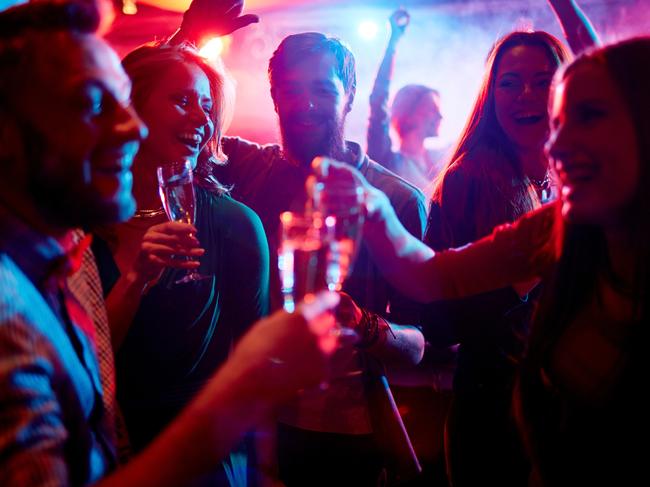 Group of young people celebrating with drinks in nightclub