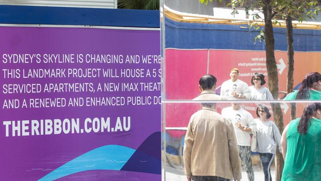 People are seen walking past signage advertising the Ribbon project at Darling Harbour. Picture: NCA NewsWire / Jenny Evans