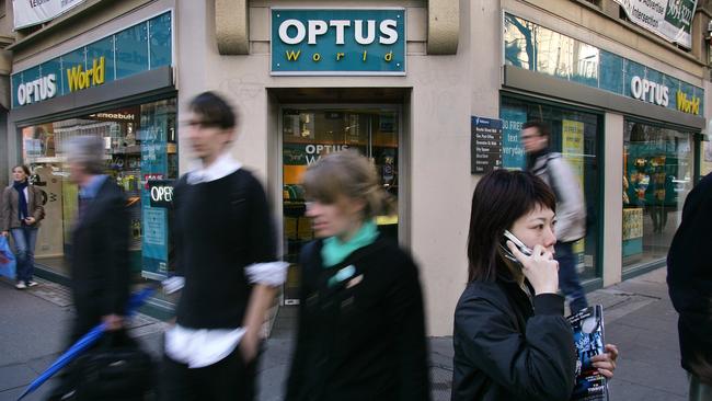 A woman speaks on a phone outside an Optus shop.