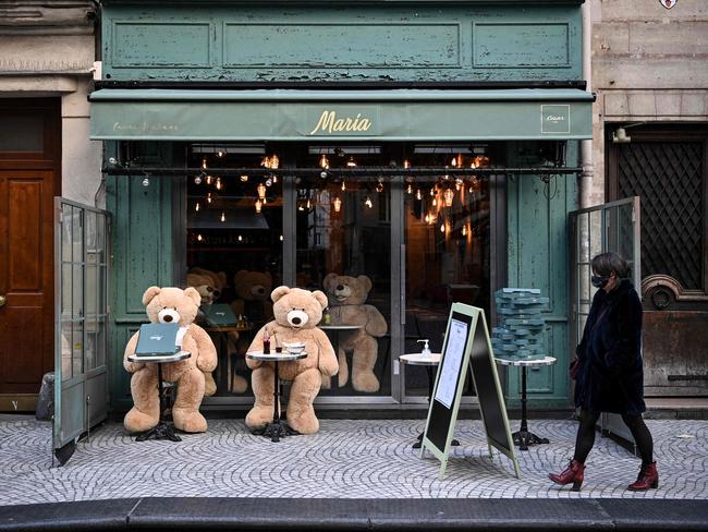 A woman walks in front of teddy bears displayed on the terrace of a closed restaurant in Paris. Picture: AFP