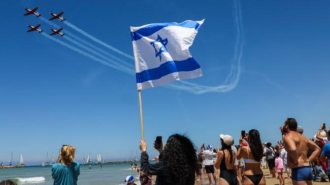 People watch Israeli Air Force aircraft flyover a beach during an airshow in Tel Aviv to mark the 75th anniversary of the State of Israel's creation. Picture: AFP