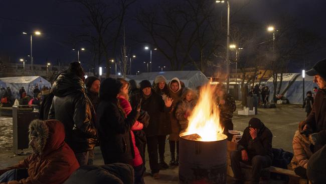 People keep warm by fires outside the main rail terminal in Lviv, Ukraine. Ukrainians from the eastern and central parts of the country have increasingly fled to western cities, which have so far been considered safer, as Russian forces advance toward Kyiv from three sides. Picture: Dan Kitwood/Getty Images