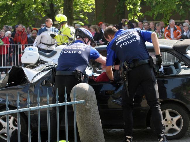 01/05/2009 WIRE: Two policemen attempt to stop the driver after he slammed with his car into Dutch festival-goers in Apeldoorn on April 30, 2009 killing five people as Queen Beatrix looked on in horror at what the driver admitted was an attack on the royal family.   Investigators said they arrested the seriously injured driver of the black car which rammed into the foot of a monument after mowing down people gathered for the annual Queen's Day royal procession in the central city of Apeldoorn. Apeldoorn mayor Fred de Graaf said 13 people were injured -- five of them seriously, and one of whom has since died. Three among the injured were children aged nine, 15 and 16.AFP PHOTO/ ANP/ BERNHARD RUEBSAMEN netherlands out - belgium out