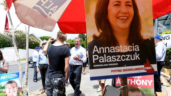 Opposition Leader Tim Nicholls (centre) walks past a sign for Queensland Premier Annastacia Palaszczuk at Ascot State School. Picture: AAP/Tracey Nearmy