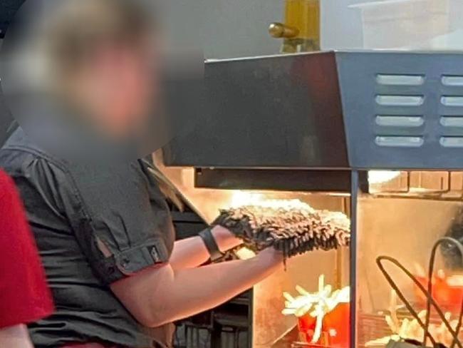 A McDonal'd worker appears to be drying a broom under a heat lamp in the fry station. Picture: Facebook