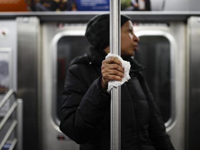 A subway customer uses a tissue to protect her hand while holding onto a pole as COVID-19 concerns drive down ridership in New York. Picture: AP