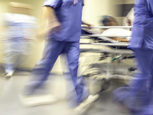 Doctors and nurses pulling hospital trolley,