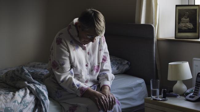 BAD AGED CARE:   A shot of a senior woman sitting on the side of her bed with her head down looking sad. She looks like she has just woken up as is dressed in nightwear.