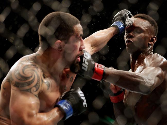 HOUSTON, TEXAS - FEBRUARY 12: Israel Adesanya (R) of Nigeria exchanges strikes with Robert Whittaker of Australia in their middleweight championship fight during UFC 271 at Toyota Center on February 12, 2022 in Houston, Texas.   Carmen Mandato/Getty Images/AFP == FOR NEWSPAPERS, INTERNET, TELCOS & TELEVISION USE ONLY ==