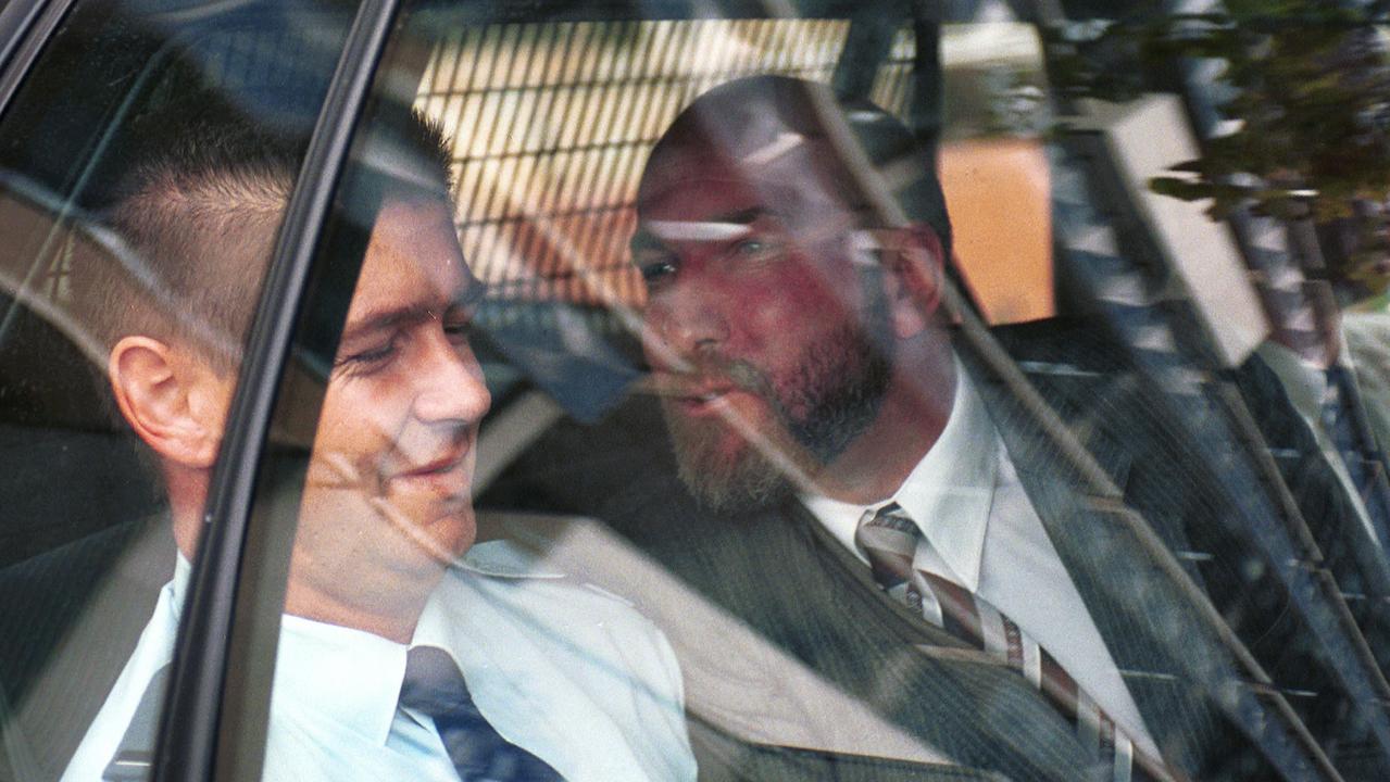 Michael Barry Fyfe, right, trying to kiss a guard on the cheek while being driven from court to Yatala Labor Prison in February 2000.