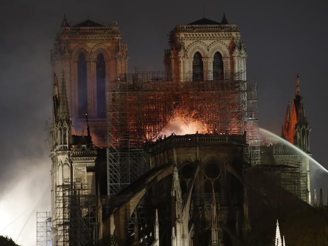 People watch Notre Dame cathedral burning in Paris, Monday, April 15, 2019. A catastrophic fire engulfed the upper reaches of Paris' soaring Notre Dame Cathedral as it was undergoing renovations Monday, threatening one of the greatest architectural treasures of the Western world as tourists and Parisians looked on aghast from the streets below. (AP Photo/Christophe Ena)