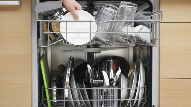 woman is using a dishwasher in a modern kitchen