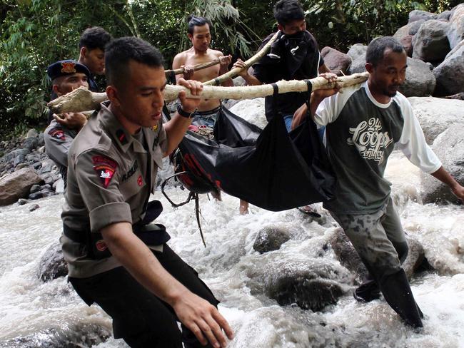 Indonesian police and villagers carry the body of a flash flood victim in Sibolangit, North Sumatra on May 16, 2016. At least eight people were killed and dozens missing May 15 in flash floods that hit the Dua Warna waterfall in Sibolangit where about 80 people were camped, an official said on May 16. / AFP PHOTO / ALBERT DAMANIK