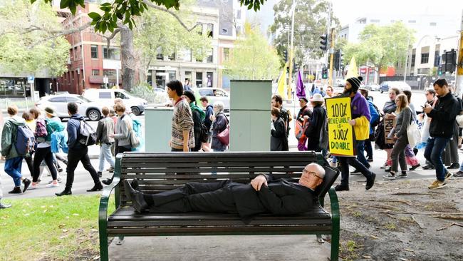 An disgruntled office worker looks on as protesters march through the CBD. Picture: Jake Nowakowski