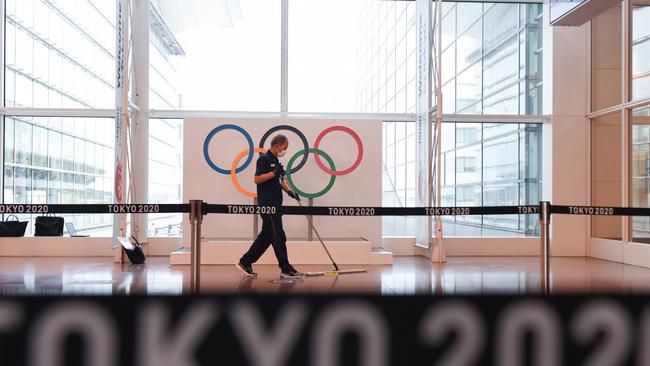 A worker sweeps in front of a banner for the Tokyo 2020 Olympic Games at Haneda Airport. Picture: Getty Images