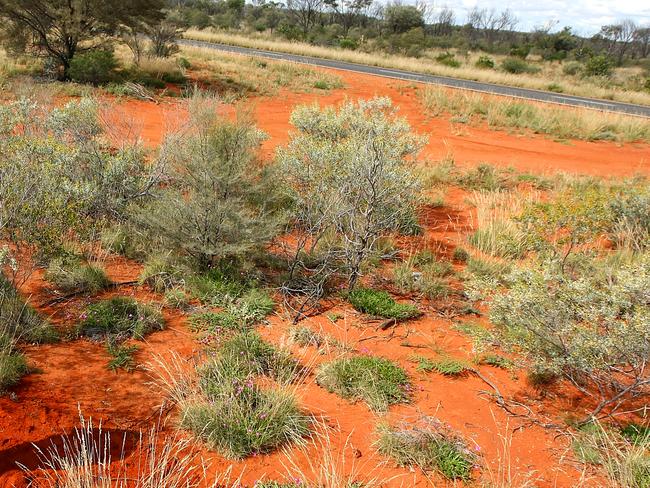 The Stuart Highway at Barrow Creek is surrounded by desert sand.