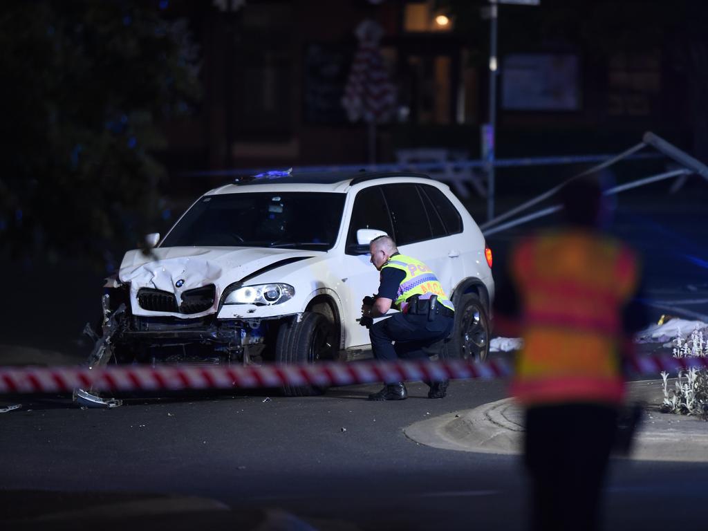 A police officer inspects the damaged BMW. Picture: Josie Hayden