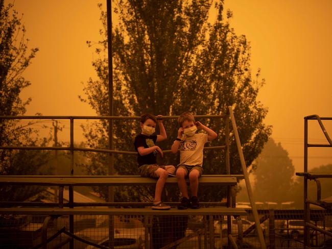 Children wear masks as they play at the showgrounds in the southern New South Wales town of Bega where people are camping after being evacuated from nearby sites affected by bushfires on December 31, 2019. - Thousands of holidaymakers and locals were forced to flee to beaches in fire-ravaged southeast Australia on December 31, as blazes ripped through popular tourist areas leaving no escape by land. Picture: Davey/AFP